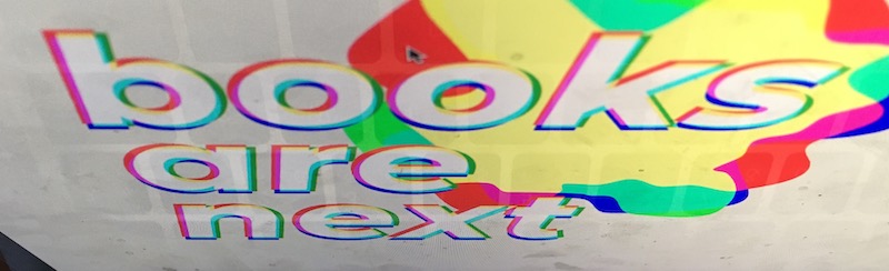 Photo of a screen with colorful text “books are next”.